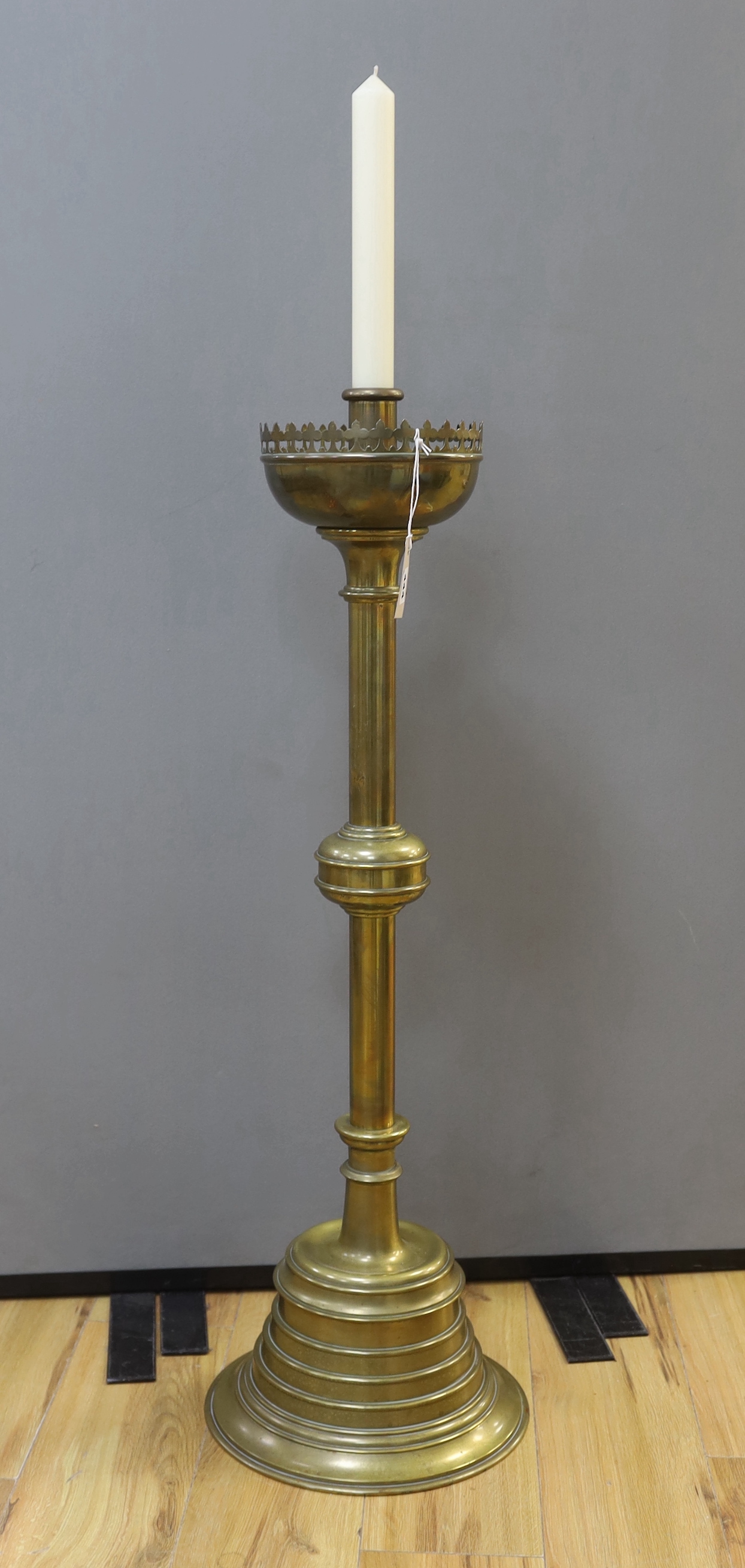 A large brass ecclesiastical candlestick with gothic border, 98cm high